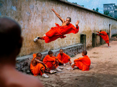 Steve-McCurry-A-Young-Monk-Runs-Along-the-Wall,-China,-2004